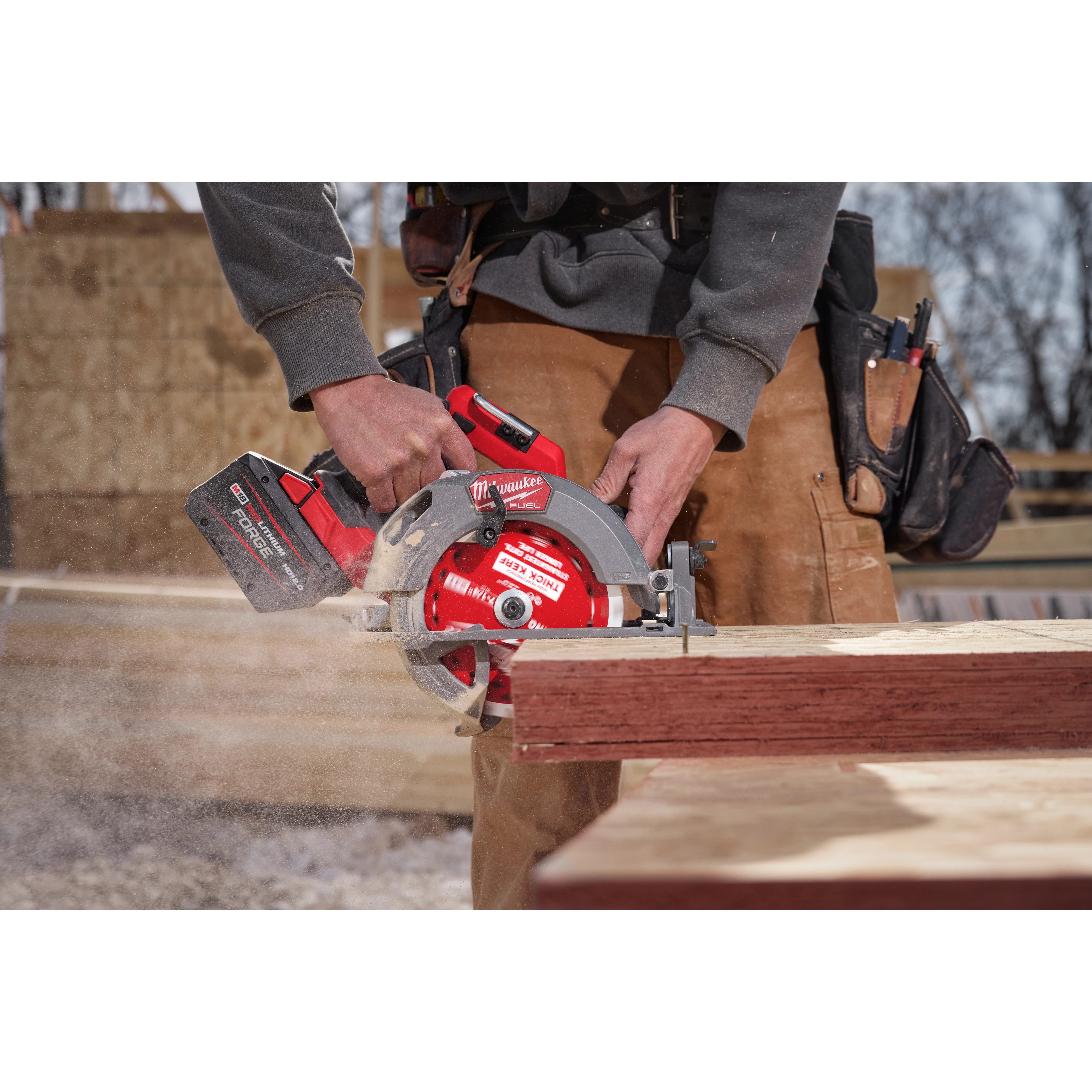 A person cuts wood using a circular saw equipped with a 7-1/4" 24T Thick Kerf Framing Circular Saw Blade. The saw is in use, generating wood dust. The person wears work clothes and a tool belt.