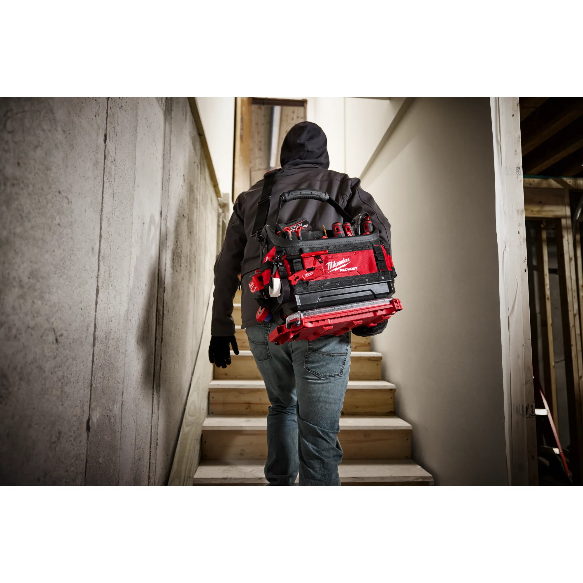 Image of the Milwaukee PACKOUT 15" Structured Tote being used by a worker on a jobsite highlighting its portability