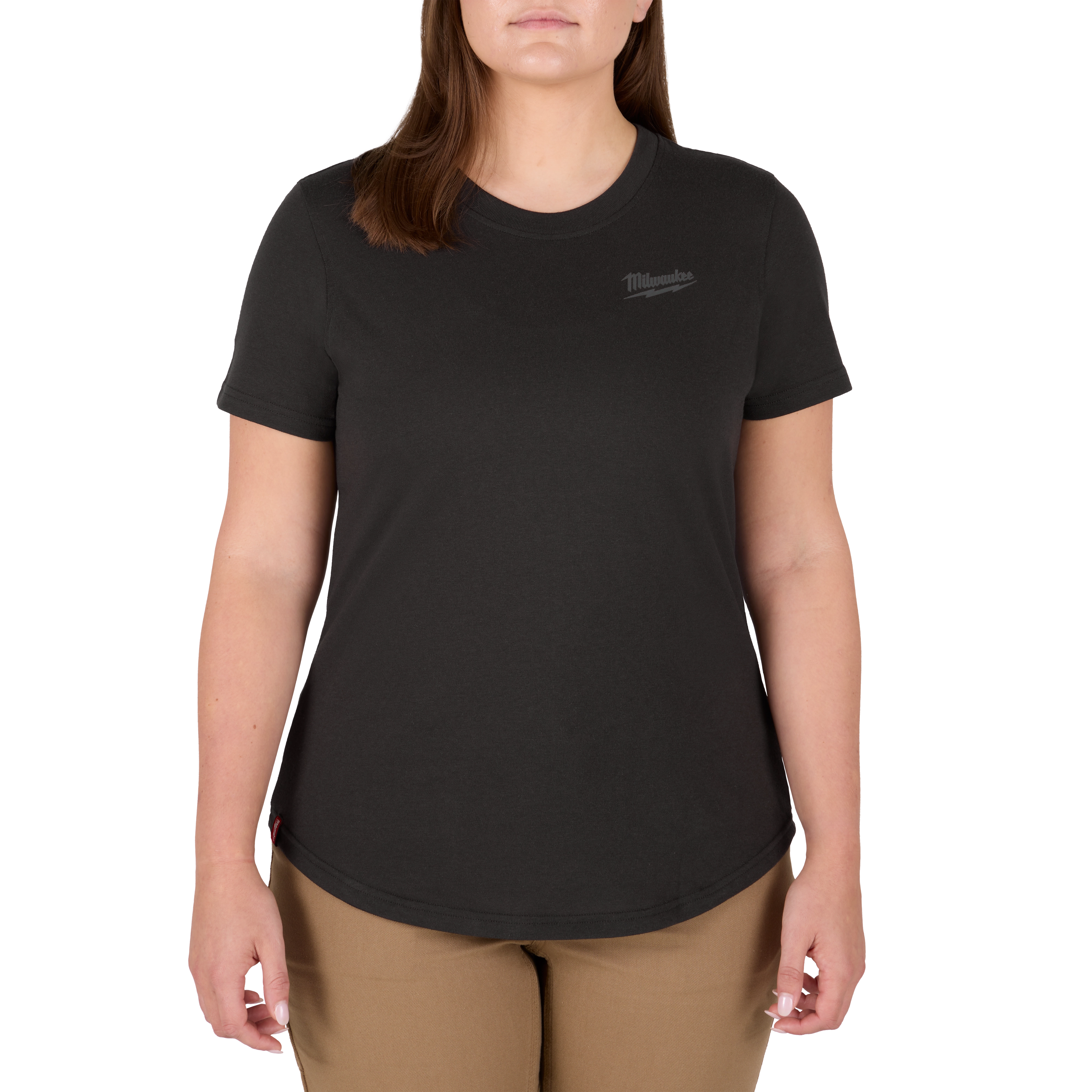 A woman is wearing the Women's FREEFLEX™ Hybrid Tee - Short Sleeve Black. The black tee has a round neckline and short sleeves, with the Milwaukee logo on the left chest. The woman is also wearing beige pants.