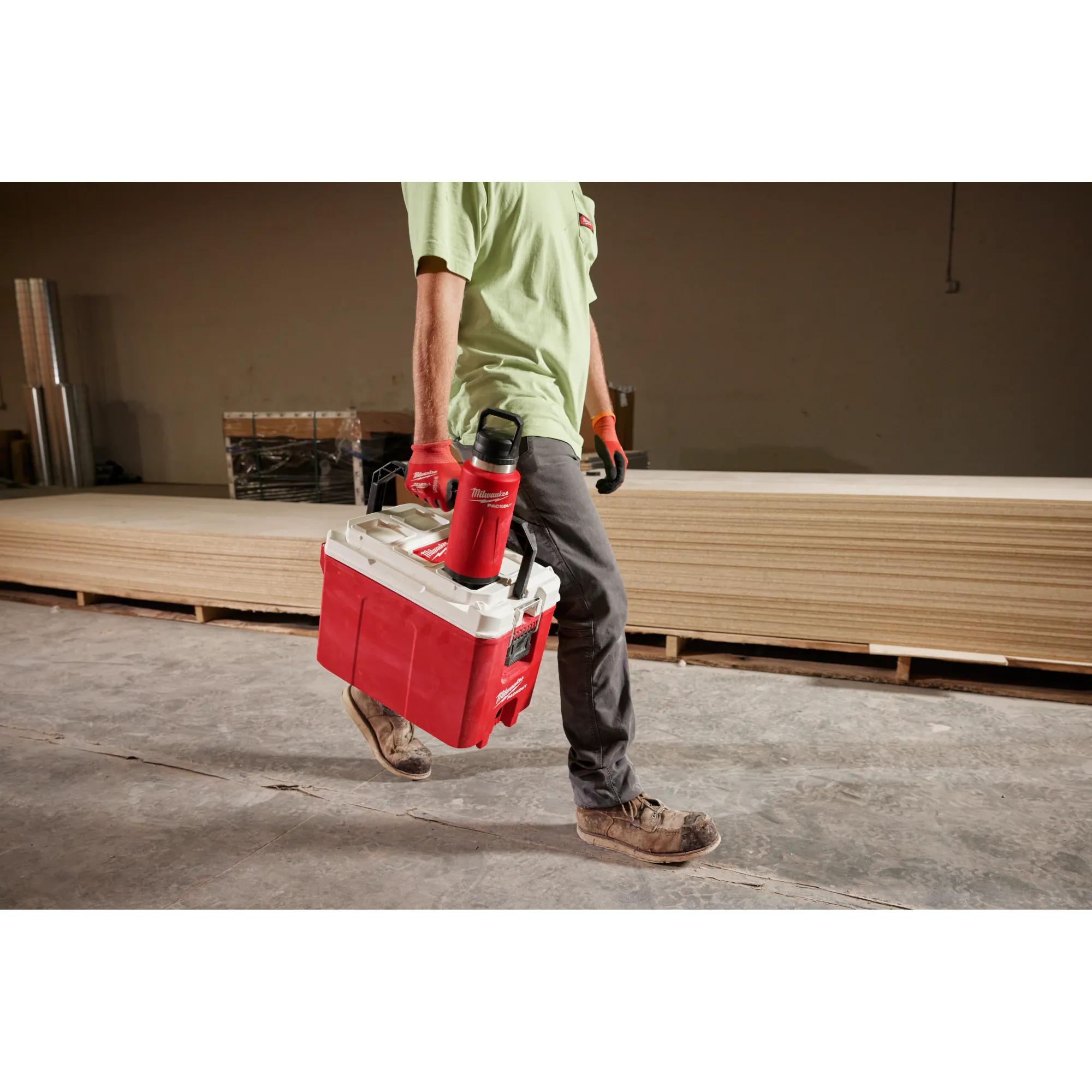 Image of a worker carrying a Milwaukee Cooler with a PACKOUT Insulated Bottle with Chug Lid in red