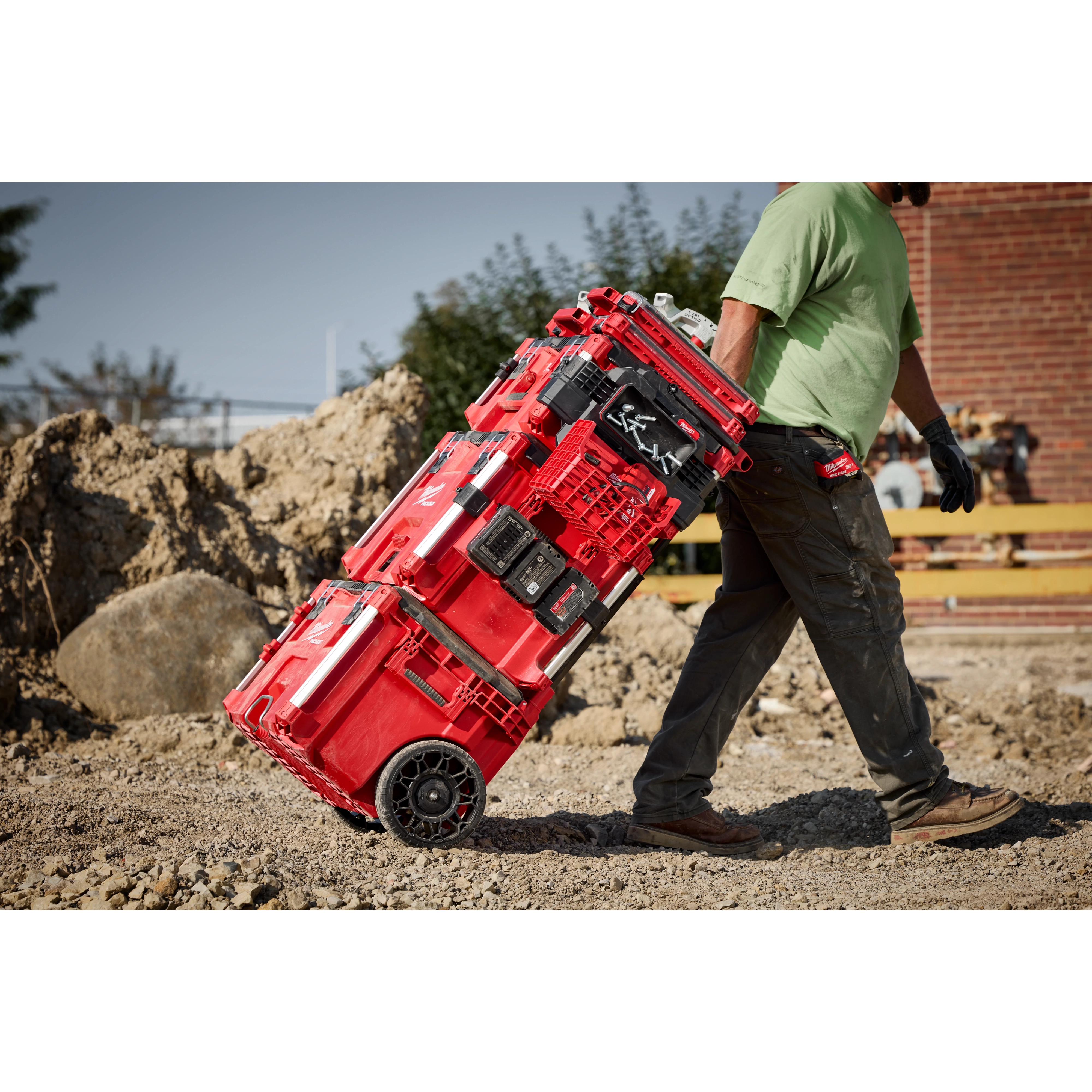 A worker transporting a PACKOUT Tool Box with PACKOUT Tool Box Compact Plate on a jobsite